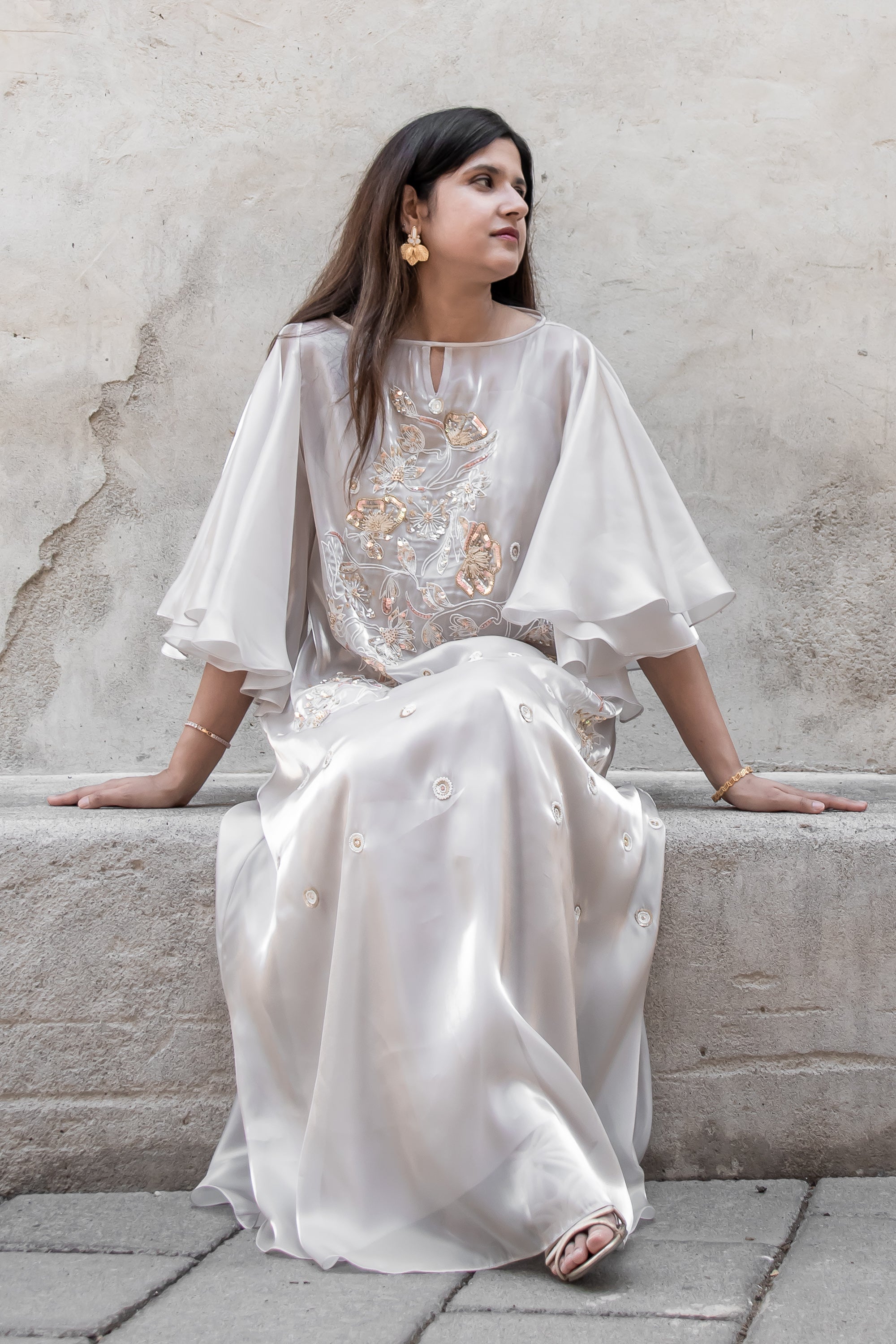 Elegant champagne organza Avelyn Kaftan showcasing layered drape and intricate hand-placed bead embellishments
