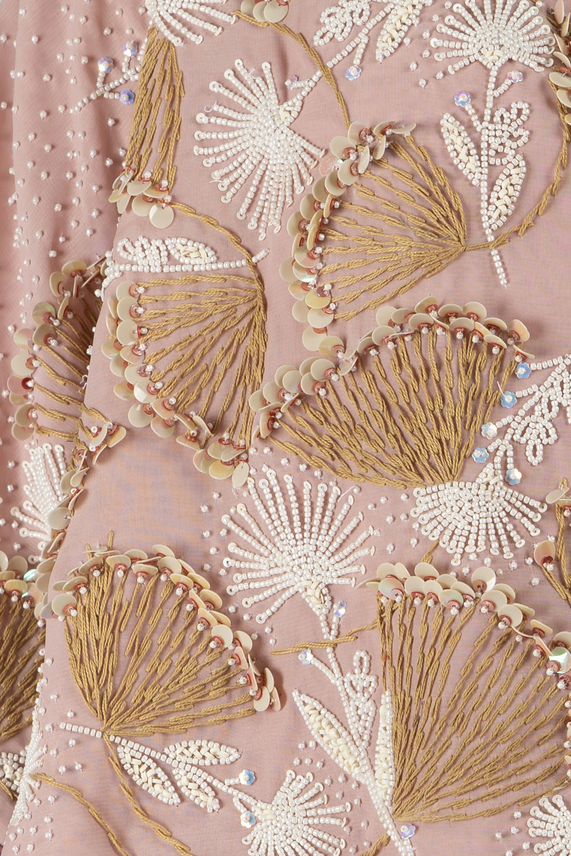 Close-up of embroidered fabric with floral patterns on a pink background.